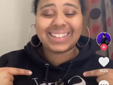 A screenshot of a TikTok with a girl smiling in a hoodie.