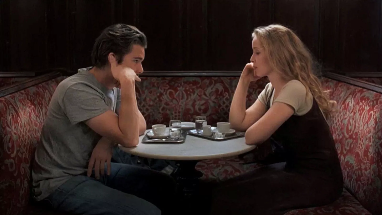 A man and woman sat opposite each other with tea at a table.
