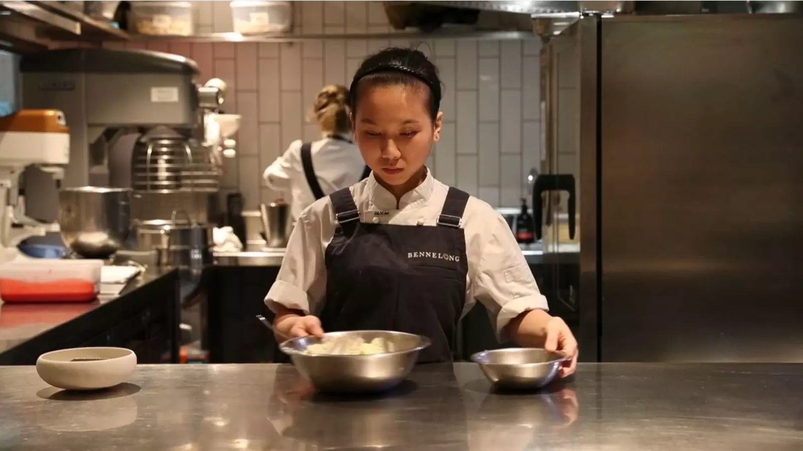 A female chef preparing food in the kitchen.
