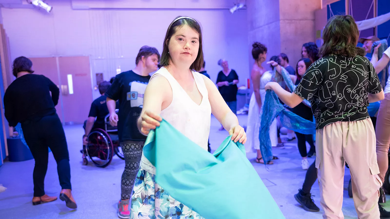 A woman holding a blue cloth and dancing.