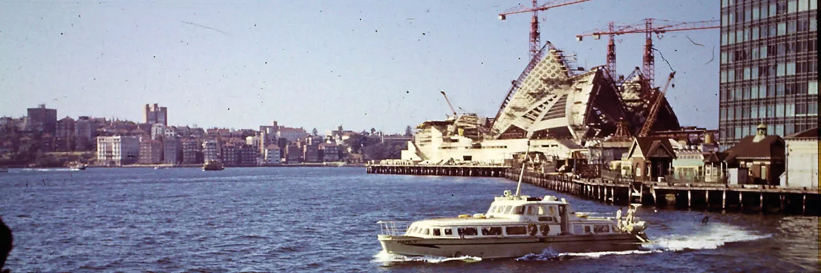 Sydney opera house under construction with cranes around the sails.