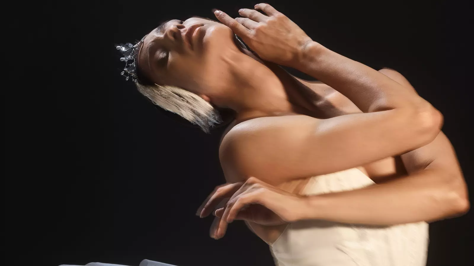 A ballerina in white dress performing on the stage.